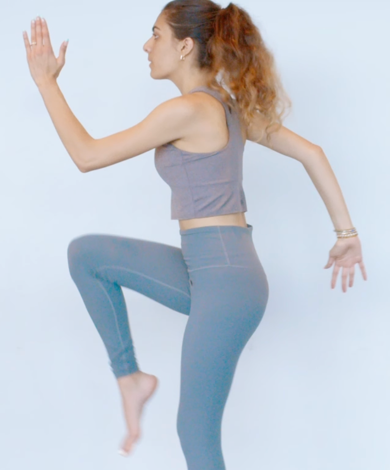 Young woman in yoga wear performing a high-knee hop.