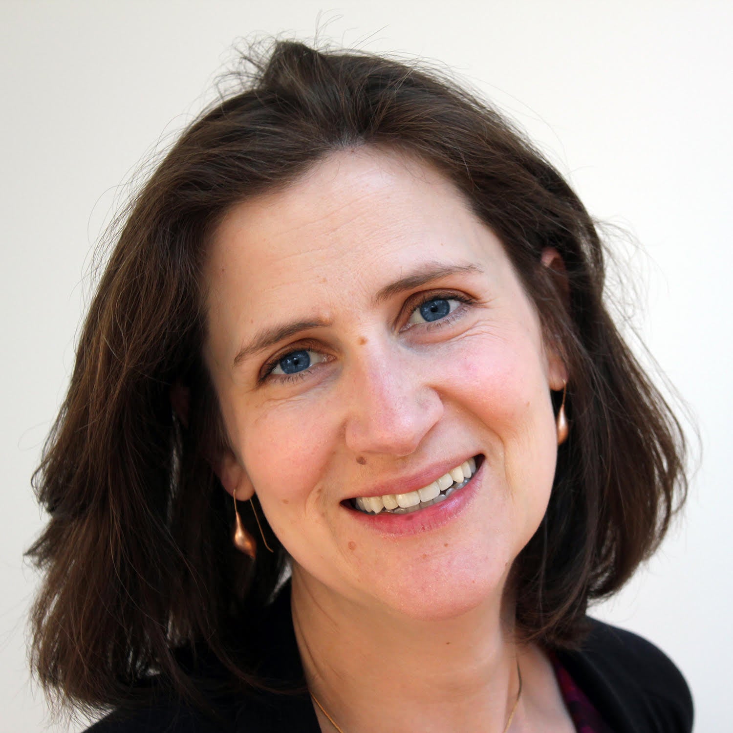 Headshot of Carly Price smiling unguardedly against a plain white background.