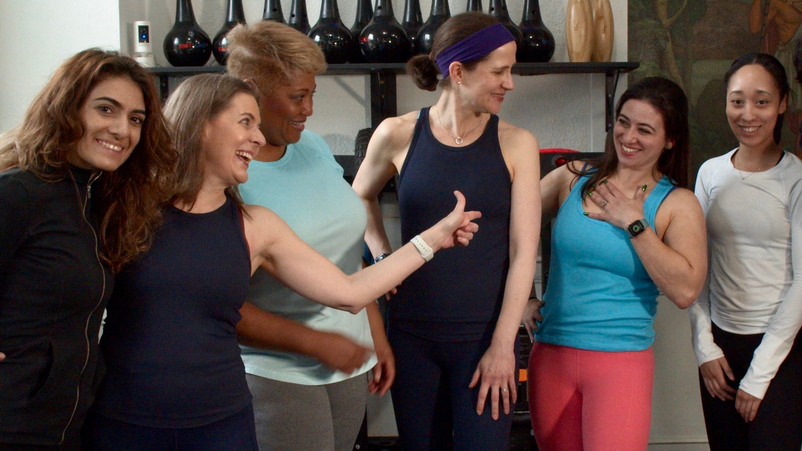 Group of women in athletic wear posing together in a gym setting